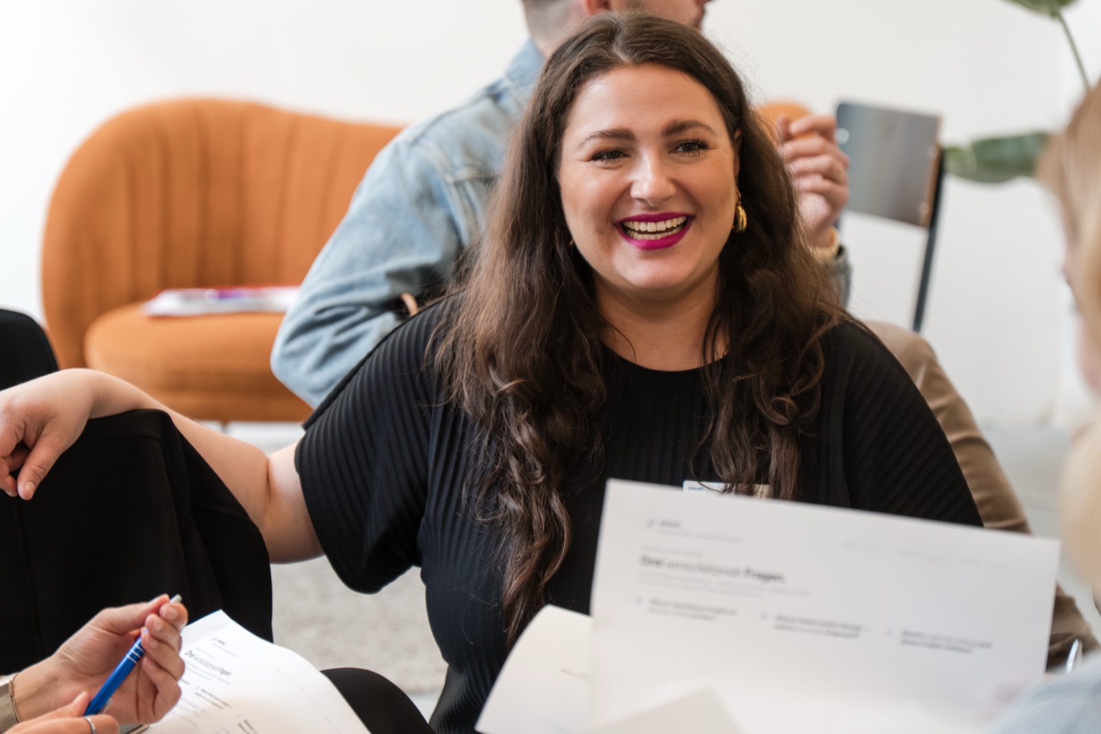 Nina lacht mit einem Arbeitsblatt in der Hand in einer Gesprächsrunde beim PACED Day